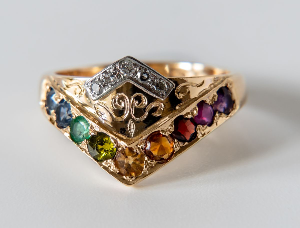 Gouden ring met een rij edelstenen in alle kleuren en een kroontje van briljanten