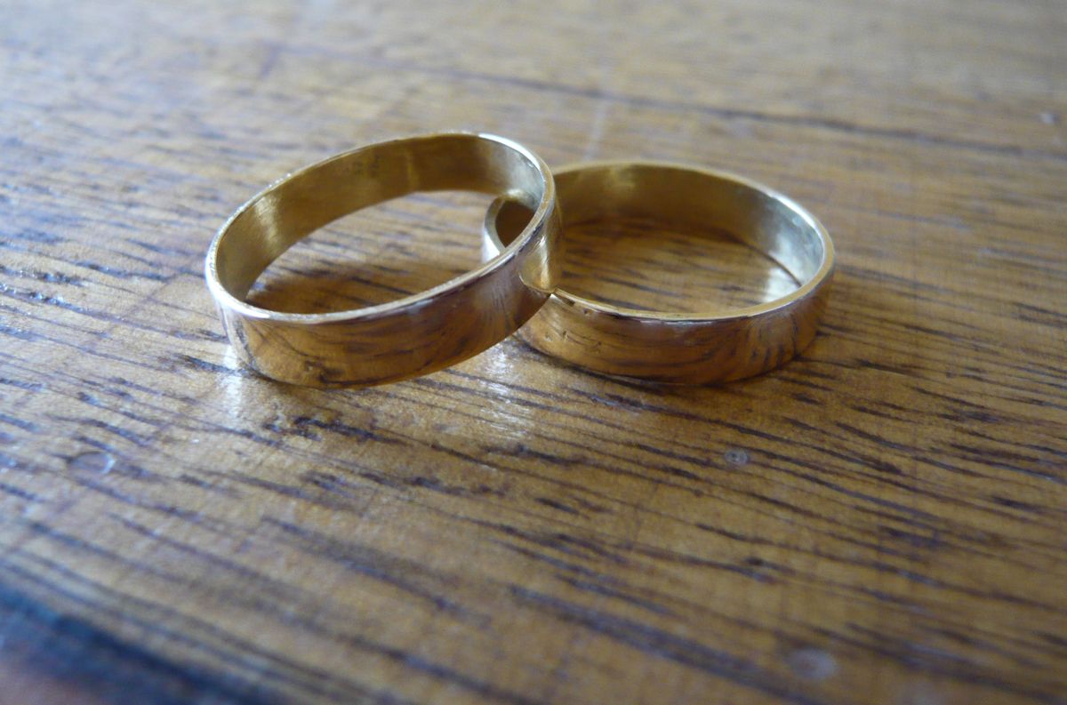 Twee gouden trouwringen op een houten tafel